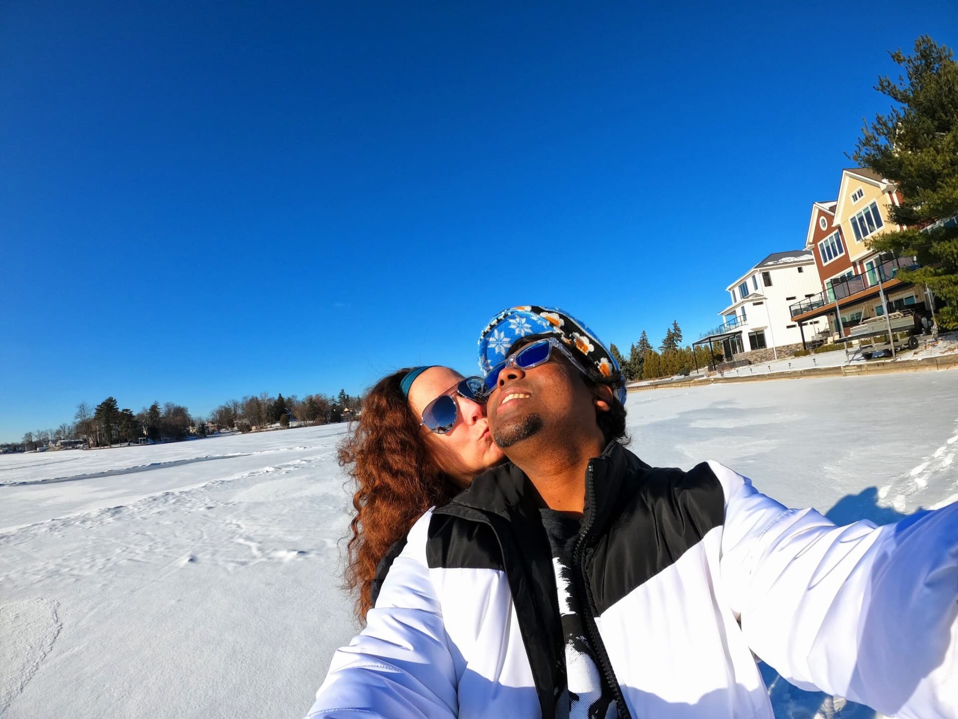 Selfie of a couple standing on a frozen lake under a deep blue winter sky
